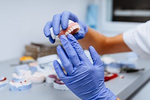 A closeup of gloved hands holding a denture